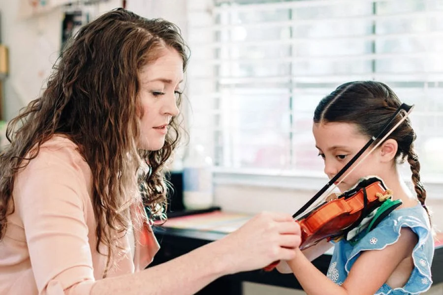 Laura Sinclair guiding a young student's bow hold in her studio